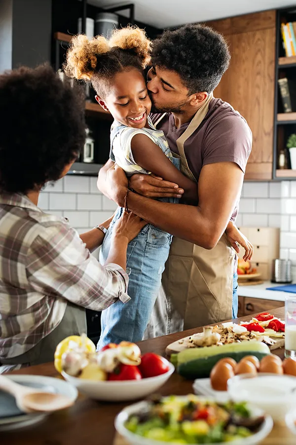 Gut-Health-Treatment A man holds his daughter and kisses her cheek as the family makes a healthy dinner in the kitchen. Get help for digestive issues and gut health from Sandra McDonald, NP in Southwestern Ontario.