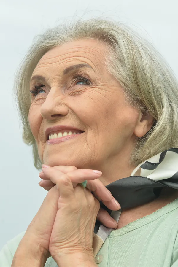 Hot-Flashes-and-Night-Sweats-Treatments An older woman holds her hands together under her chin and looks up at a cool sky smiling. Get treatment for hot flashes and night sweats from Sandra McDonald, NP in Southwestern Ontario.