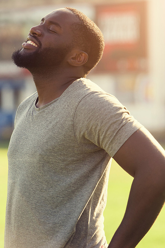 Lean-Muscle-and-Recovery-Treatment A black man in a gray t-shirt and smiles, looking up with closed eyes after a satisfying workout. Get treatment for lean muscle loss and recovery from Sandra McDonald, NP in Southwestern Ontario.