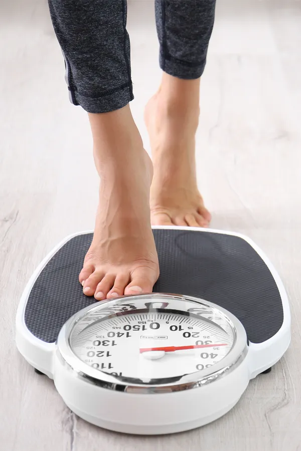 Obesity-Treatment Close up of feet stepping onto a scale. Receive expert functional medicine for obesity treatment by Sandra McDonald, NP in Southwestern Ontario.