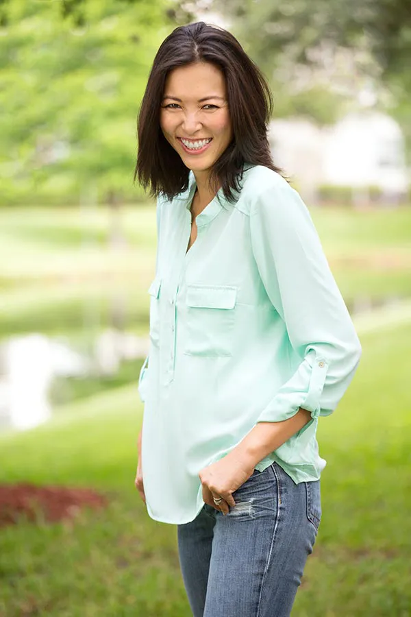 Perimenopause-Treatment A middle-aged brunette woman in a light green button-up shirt stands outside smiling, happy with her perimenopause treatment from Sandra McDonald, NP in Southwestern Ontario.